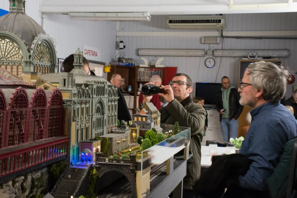 Man met fototoestel bij modelspoorbaan